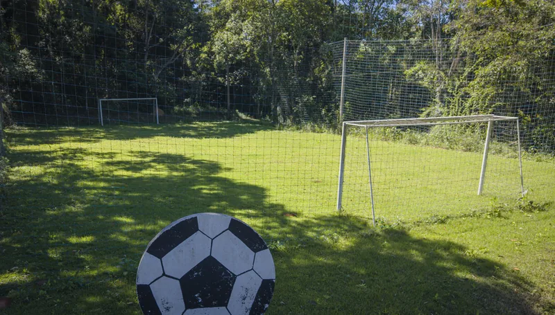 Campo de futebol gramado, com traves e rede de proteção